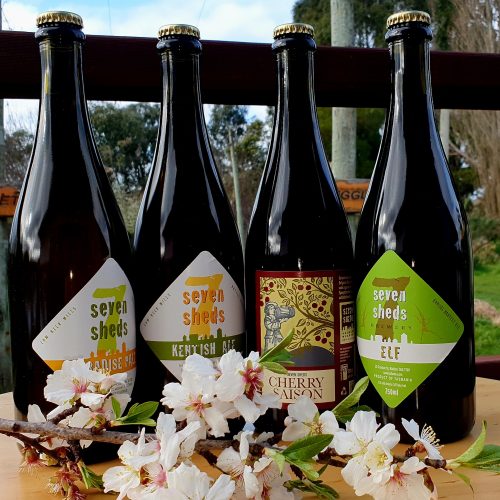 Four bottles of different beers offered in Seven Sheds Spring Selection, with almond blossoms in the foreground to emphasise spring.